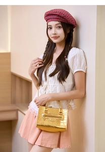 Detailaufnahme der goldenen Kroko-Handtasche mit Reißverschluss an einem weiblichen Model