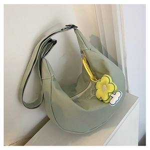Détail du sac demi-lune vert clair avec texture gaufrée et breloque tournesol