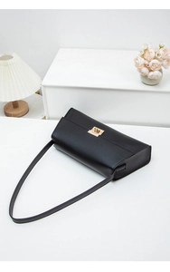 Sac sous le bras minimaliste en cuir noir avec fermoir doré sur une surface blanche