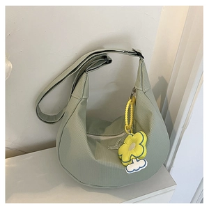 Détail du sac demi-lune en velours côtelé vert clair avec pendentif tournesol jaune