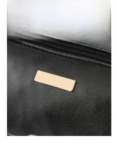 Detailaufnahme der schwarzen Zylindertasche aus Leder mit goldener Metallplatte