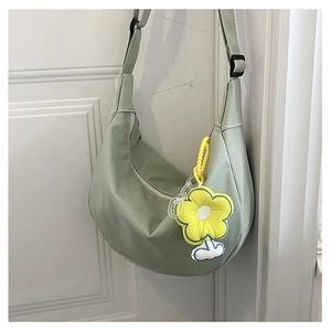 Détail du sac demi-lune vert clair avec texture nervurée et breloque fleur jaune
