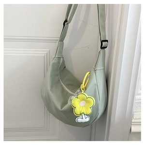 Détail du sac croissant vert clair avec texture douce et pendentif fleur jaune