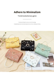 Detail of embroidered floral crossbody bags with pearl handles and metal magnetic clasps