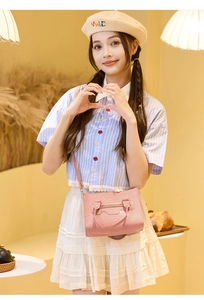 Detailansicht einer rosa Handtasche mit Krokodilprägung, Metallnieten und Schultergurt