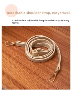 Detail of beige leather strap with adjustable golden buckles and metal hooks on wood
