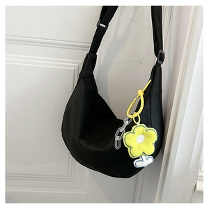 Détail d'un sac demi-lune noir en nylon avec un charmant pendentif fleur jaune
