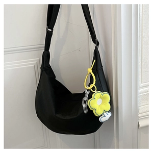 Détail du sac bandoulière demi-lune noir avec breloque fleur jaune sur porte blanche