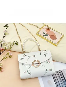 Detail of white PU leather bag with floral embroidery and pearl handle close-up