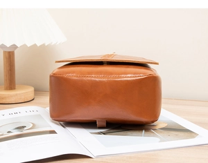 Detail view showing the bottom construction and texture of brown oil wax leather backpack