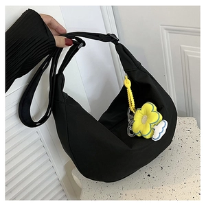 Détail d'un sac demi-lune noir avec un pendentif fleur de tournesol jaune