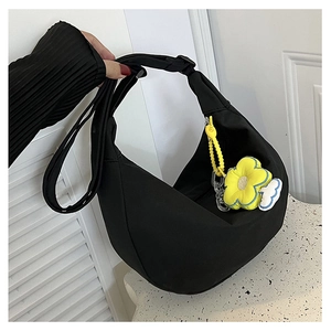 Détail du sac bandoulière noir en demi-lune avec un pendentif fleur jaune vif