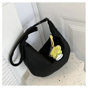 Détail du sac hobo en nylon noir avec bandoulière réglable et breloque fleur jaune