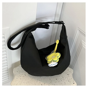 Détail du sac bandoulière noir en demi-lune avec un pendentif tournesol jaune sur le zip