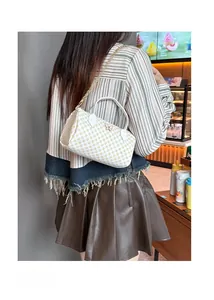 Detail of white Boston bag featuring yellow lattice print and golden butterfly charm