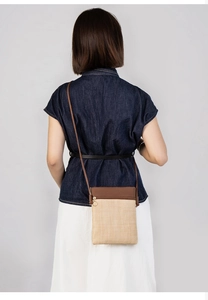 Detail view of woven fabric crossbody bag with brown leather trim on female model
