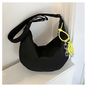 Détail du sac bandoulière croissant noir avec breloque fleur jaune et chaîne