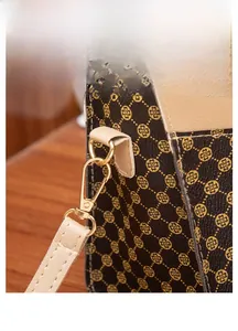 Close-up of golden hardware and leather stitching on brown printed fashion handbag