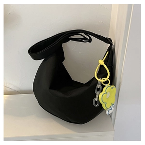 Détail du sac demi-lune en nylon noir avec breloque tournesol jaune et chaînette
