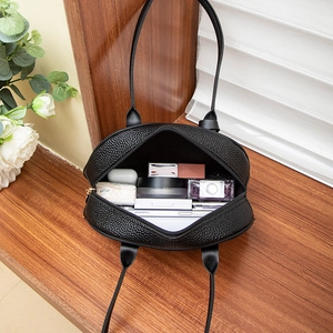 Large black lychee pattern leather bowling handbag with gold zipper showing interior capacity