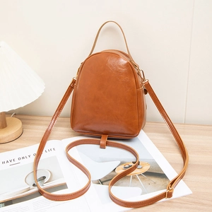 Brown vintage oil wax leather backpack with gold zippers on a wooden table setup
