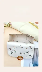 Detail view of white floral embroidered handbag featuring multi-layer storage compartments