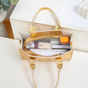 Golden crocodile pattern handbag showing spacious interior with cosmetics and phone