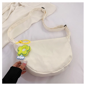 Détail du sac demi-lune en toile blanche avec breloque fleur jaune et bandoulière