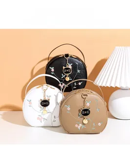 Detailed display of three semi-circle handbags featuring floral embroidery and cat charms