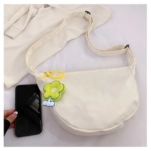 Détail du sac croissant en toile blanc cassé avec breloque fleurie et bandoulière
