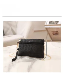 Dettaglio della borsa a busta nera intrecciata con dimensioni 22x13cm su piano marmo