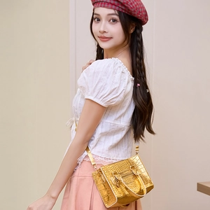 Metallic gold crocodile pattern handbag with crossbody strap shown on fashion model