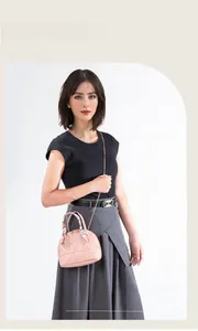 Detailed view of a pink quilted shell bag with a scarf-wrapped handle and gold chain