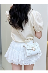 Detail of floral embroidered white crossbody bag with pearl handle and golden chain