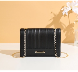Details der schwarzen Lederhandtasche mit goldener Kette und metallischem Logo