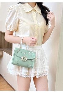 Close-up of pearl handle and floral embroidery on mint green crossbody small square bag
