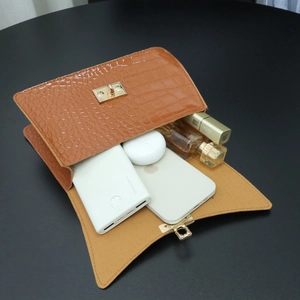 Brown crocodile pattern handbag with gold rotary lock showing internal storage capacity