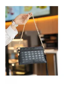 Dettaglio pochette trapuntata nera con elegante tracolla a catena dorata in caffè