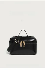 Detail of black glossy textured box bag featuring dual zippers and gold hardware