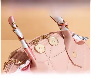 Detail of pink quilted bag featuring golden zipper and handle wrapped in printed silk scarf