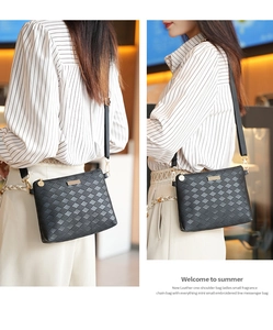 Detail showing black woven leather cross-body bag with gold hardware and shoulder strap