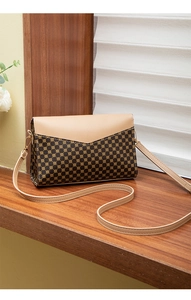 Detail of a patterned crossbody bag with geometric gold prints on a dark brown surface