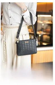 Close-up of black woven leather envelope bag with tassels and crossbody strap