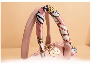Detail of pink leather handbag handle with a decorative floral silk scarf and gold zipper
