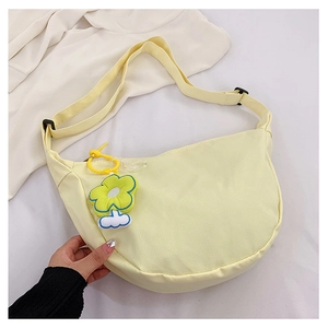 Détail du sac croissant en toile jaune pâle avec breloque fleur verte et sangle
