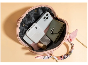 Pink round shell bag showing spacious interior with phone, wallet and cosmetics items