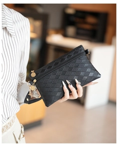 Dettaglio della trama trapuntata nera sulla pochette da donna con zip dorata e ciondolo
