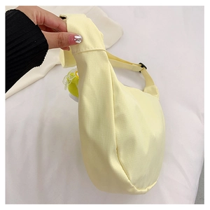 Détail du sac hobo en toile jaune pâle avec sangle réglable et breloque jaune ronde