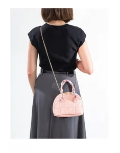 Pink quilted shell crossbody bag with silk scarf handle on a female model