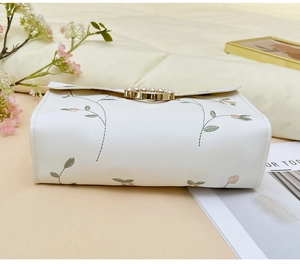 Detailed embroidery of floral vines and pearl-inlaid gold buckle on a beige square bag